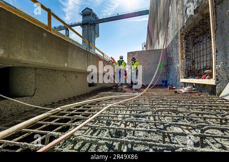 Bauarbeiter führen Arbeiten an der Betoneinspeisung des Kammerbodens für das Projekt Charleroi Lock Construction an den Monongahela River Locks and Dam 4 in Charleroi, Pennsylvania, am 21. März 2023 durch. Die USA Das Armeekorps der Ingenieure im Bezirk Pittsburgh betreibt die Anlage und beaufsichtigte das Bauprojekt in Charleroi zur Verbesserung der Binnenschifffahrt in der Region. Die neu errichtete Kammer soll sich vor dem Sommer mit Wasser füllen, und sie soll 2024 vollständig in Betrieb gehen. Die Bauarbeiten in Charleroi begannen 2004. Nach Abschluss des Projekts Charleroi werden Kosten anfallen Stockfoto