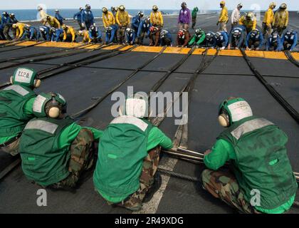 US Navy Air Department Personal dehnt die Absperrseile auf Position Stockfoto