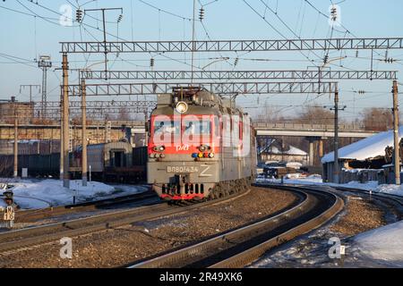 SHARYA, RUSSLAND - 19. MÄRZ 2022: VL80S elektrische Lokomotive mit Güterzug verlässt den Bahnhof an einem sonnigen Märzabend Stockfoto