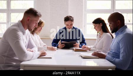 Gruppe von Jungen multiethnischen Menschen Lesen der Bibel über Holz- Schreibtisch Stockfoto