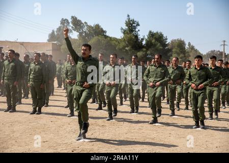 Mitglieder der syrischen Akademie der inneren Sicherheitskräfte marschieren während einer Abschlusszeremonie in der Region al-Shaddadi, Syrien, 3. April 2023. Personal des Detention Capabilities Assessment Teams, das der Alpha Company zugewiesen ist, 1-148. Infanterie, 37. Infanteriebrigade-Kampfteam, Task Force Buckeye führt mit Partnern aus Asayish Grundlagenkurse zur Strafverfolgung durch, um sie mit den Fähigkeiten auszustatten, die erforderlich sind, um Nordost-Syrien gegen den ISIS zu sichern. Koalitionstruppen beraten, unterstützen und unterstützen die syrischen demokratischen Kräfte bei der dauerhaften Niederlage des ISIS. Stockfoto