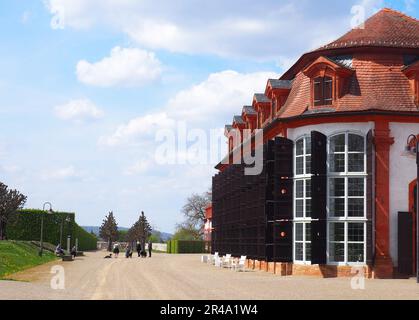 Ein rot-weißes zweistöckiges Gebäude steht an einer Straßenseite, umgeben von grünen Bäumen Stockfoto