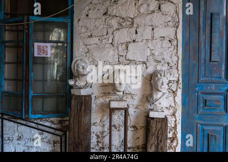 Drei menschliche Skulpturen auf einem Podium vor einer alten Steinmauer Stockfoto