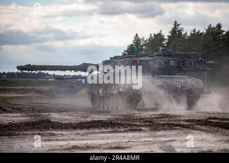 Deutsche Soldaten, die dem 93. Panzerlehr-Demonstrationsbataillon, 9. Panzerlehr-Brigade, 1. Panzerdivision, zugeteilt wurden, fuhren während einer kombinierten Feuerübung in Bemowo Piskie, Polen, am 3. April 2023 einen Leopard 2A6-Panzer auf das Gelände. Die Mission der 4. Infanterieabteilung in Europa besteht darin, sich an multinationalen Schulungen und Übungen auf dem ganzen Kontinent zu beteiligen und mit NATO-Verbündeten und regionalen Sicherheitspartnern zusammenzuarbeiten, um V Corps, Amerikas zukunftsgerichtetes Korps in Europa, mit Kampfkräften zu versorgen. Stockfoto