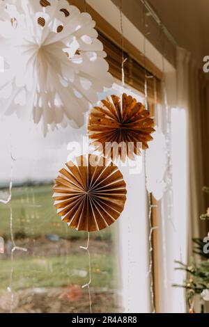 Nahaufnahme eines Fensters mit festlichen Ornamenten und einem Weihnachtsbaum im Hintergrund Stockfoto