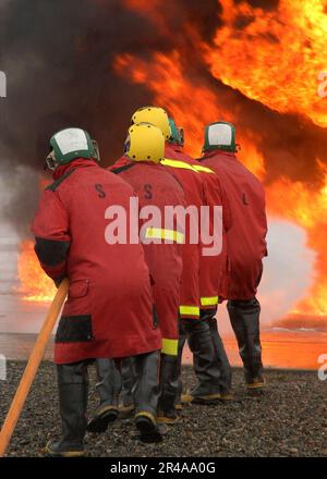 US Navy Eine Feuerwehr auf dem Cockpit der Küstenwache Cutter Polarsee bekämpft ein kontrolliertes Feuer Stockfoto