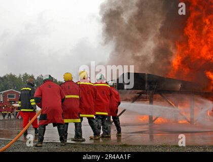 US Navy Eine Feuerwehr auf dem Cockpit der Küstenwache Cutter Polarsee bekämpft ein kontrolliertes Feuer Stockfoto