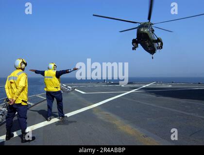 DIE BESATZUNGSMITGLIEDER der US Navy Landing Signal signalisieren einen UH-3H Sea King Hubschrauber, der den Helikoptern der Anti-U-Boot-Staffel Light Five One (HSL-51) zugeteilt ist, auf dem Flugdeck der USS Blue R. Stockfoto