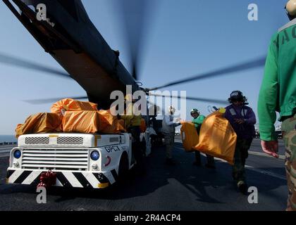 Mitglieder der US Navy Crew entladen tausende Pfund Post aus dem Frachtraum eines 53E Sea Dragon Hubschraubers Stockfoto