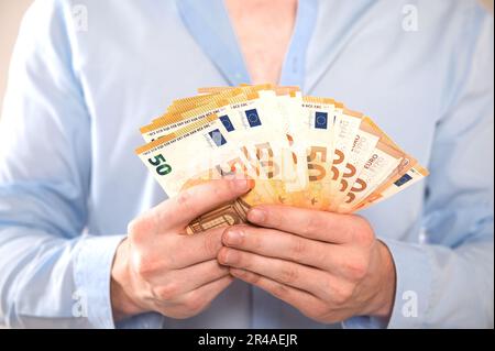 Ein Mann hält ein Bündel 50-Euro-Scheine in beiden Händen. Stockfoto