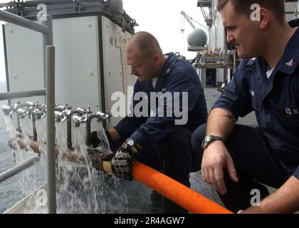 US Navy Hull Maintenance Technician 1. Class Left und Hull Maintenance Technician 3. Class testen einen Verteiler für Frischwasser Stockfoto