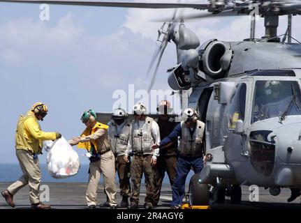 Mitglieder der US Navy Crew an Bord der USS Abraham Lincoln (CVN 72) laden Spielzeugtaschen in einen HH-60H Seahawk Helikopter Stockfoto