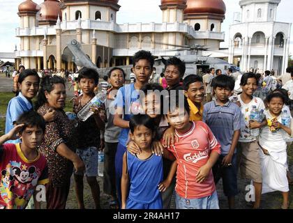 US Navy Children of Meulaboh, Sumatra, Indonesien, trinken das lange erwartete Wasser, das ein HH-60H Seahawk Helikopter erwartet Stockfoto