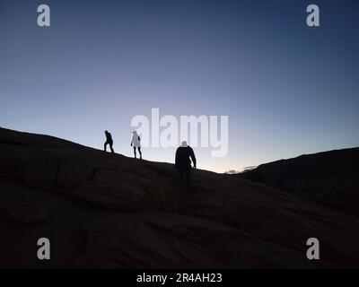 Eine Gruppe von Personen, die auf einem Hügel spazieren und den Sonnenuntergang genießen Stockfoto