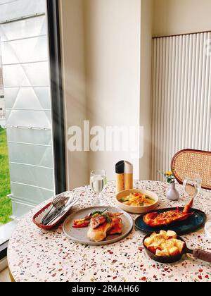 Eine frisch zubereitete Mahlzeit auf einem Tisch vor einer Glastür Stockfoto