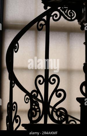 Ein Metallgeländer im Vintage-Stil mit Silhouette vor einem hellen Fenster Stockfoto
