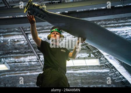 SINGAPUR (7. März 2023) Aviation Machinist's Mate 3. Class Brendon Johnson, Left, zugewiesen zum Helicopter Maritime Strike Squadron (HSM) 35, aus Queen Creek, Arizona, führt einen Hauptrotor eines MH-60R SeaHawk, der an HSM 35 befestigt ist, Ausstieg aus dem Hubschrauber in der Hangar Bay an Bord des Küstenschiffes USS Oakland (LCS 24) der Independence-Klasse in Singapur, 7. März 2023. Oakland, Teil der Destroyer-Staffel 7, ist im Rotationseinsatz, operiert im US-Flottengebiet 7., um die Interoperabilität mit Alliierten und Partnern zu verbessern und als einsatzbereite Einsatztruppe zur Unterstützung einer freien zu dienen Stockfoto