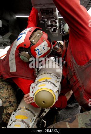 US Navy USA Marinekorps Ordnancemen laden eine GBU-38 500 Pfund Satelliten-gesteuerte Bombe auf eine der F-A-18A-Hornets des Geschwaders, bevor sie an Bord der USS Harry S. Truman (CVN 75) fliegen. Stockfoto