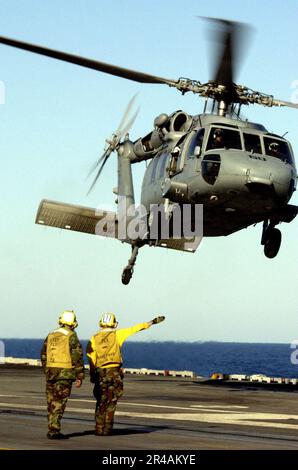 US Navy Landing Signal Engelistete Mitarbeiter signalisieren an einen MH-60s Nighthawk, der der Sideflares von Helicopter Combat Support Squadron One (HC-11) zugeteilt ist, wenn es vom Cockpit der USS Ronald Reagan (C Stockfoto