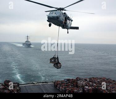 US Navy ein MH-60s Seahawk Hubschrauber hebt zwei Paletten mit Vorräten aus dem Cockpit des schnellen Kampfschiffs USNS Arctic (T-AOE 8) des militärischen Sealift Command (MSC) während einer vertikalen Auffüllung des Stockfoto