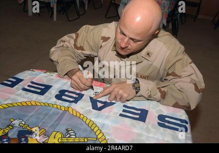 LIEUTENANT Commander der US Navy. Der Navy Chaplain, der dem mobilen Baubataillon Two Three (NMCB-23) zugeteilt ist, unterzeichnet eine Seabee-Flagge. Stockfoto