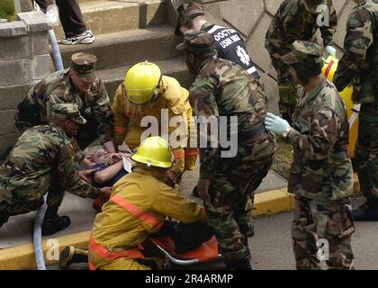 US Navy USA Marinesicherheitspersonal und Feuerwehrleute, die an der regionalen Feuerwehr des Kommandanten der Marine angeschlossen sind, simulieren eine Übung mit Todesopfern, die an Bord der Flottenaktivitäten Yokosuka, Japan, durchgeführt wird. Stockfoto