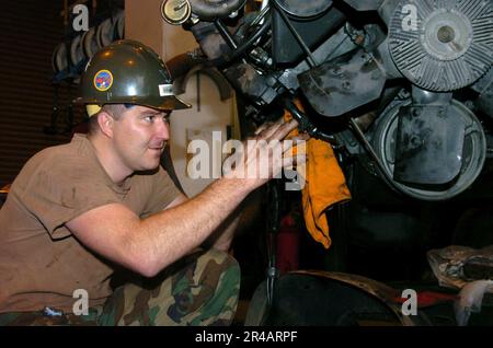 US Navy Construction Mechanic Klasse 3. prüft einen Motor auf Undichtigkeiten, bevor er in einen Chevy Coupe V-Lkw in Okinawa, Japan, eingebaut wird. Stockfoto