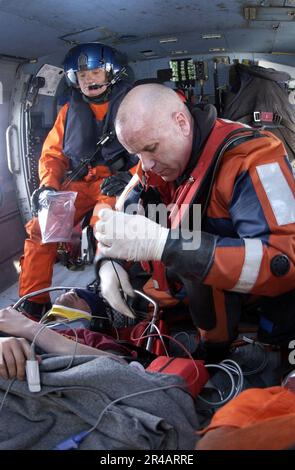 US Navy USA Küstenwache Petty Officer 1. Klasse A Rettungsschwimmer zugewiesen zur Küstenwache Luftwaffe Cape Cod, rechts, überwacht die Vitalfunktionen eines verletzten Fischers in der Kabine eines HH-60 Ja Stockfoto