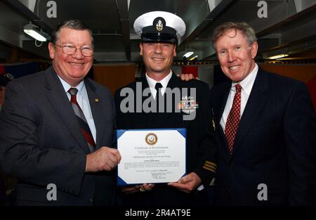 US Navy Rep. Randy Duke Cunningham (R-CA), Left, und Bill Irish Driscoll, Right, legen dem Chief Operations Specialist an Bord der USS Ronald Reagan (CVN 76) ein neues Einstellungszertifikat vor. Stockfoto