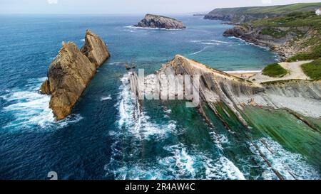 Atemberaubende Küstenformation mit majestätischen Felssäulen, die aus dem Meer aufsteigen und gegen die Wellen schlagen. Canales de los Urros, Arnia, Liencre Stockfoto