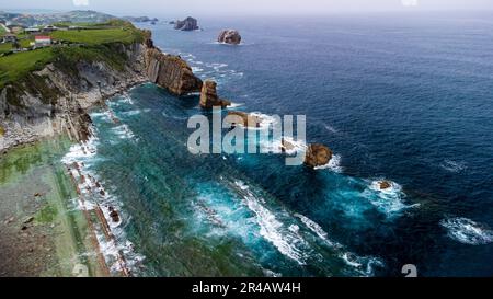 Atemberaubende Küstenformation mit majestätischen Felssäulen, die aus dem Meer aufsteigen und gegen die Wellen schlagen. Canales de los Urros, Arnia, Liencre Stockfoto