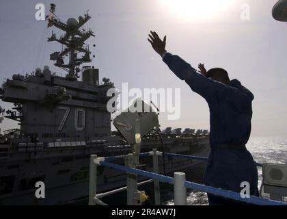 US Navy A Signalman verwendet Semaphor, um über Handsignale mit Seeleuten an Bord des Flugzeugträgers USS Carl Vinson (CVN 70) der Nimitz-Klasse zu kommunizieren. Stockfoto