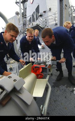 MATROSEN DER US Navy, die im Sonarladen an Bord des geführten Raketenzerstörers USS Mustin (DDG 89) arbeiten, laden einen MK-46 Mod 5A(SW) Torpedo. Stockfoto