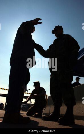 US Navy Ein Mitglied des Force Protection Training Team (FPTT) lässt einen Metalldetektor über einem Matrosen laufen, der während einer Force Protection Exercise (FPEX) an Bord der Naval Station Norfolk, Virginia, die angemessene physische Sicherheit gewährleistet Stockfoto