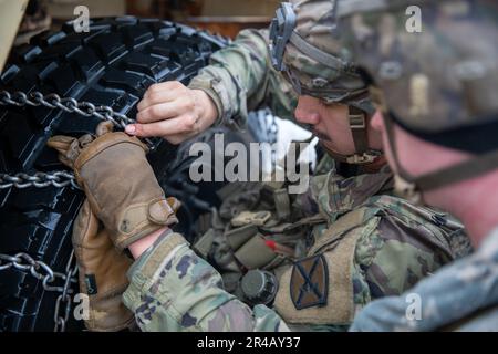 10. Bergsoldaten arbeiten zusammen, um Schneeketten auf einem HMMV in weniger als 10 Minuten zu platzieren. Die Teams konkurrieren um die schnellste Zeit, bevor sie mit der nächsten Übung fortfahren. Stockfoto