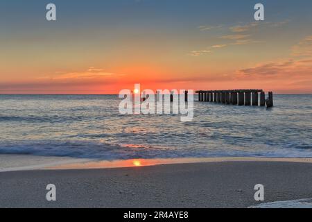 Ein atemberaubender Sonnenuntergang auf Boca Grande Island, Florida, ist beleuchtet auf einem alten Steinpier Stockfoto