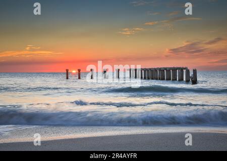 Ein atemberaubender Sonnenuntergang auf Boca Grande Island, Florida, ist beleuchtet auf einem alten Steinpier Stockfoto
