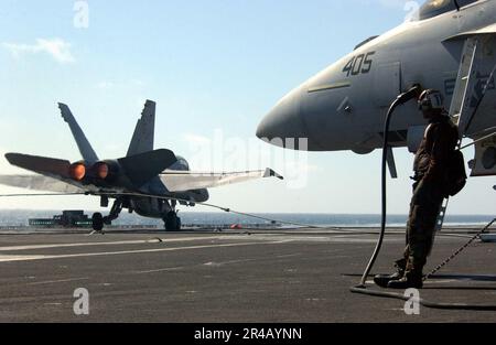 US Navy Ein Flugzeugkapitän beobachtet ein Marine Corps F-A-18D Hornet, während es an Bord des Flugzeugträgers USS Ronald Reagan (CVN 76) festgenommen landet. Stockfoto