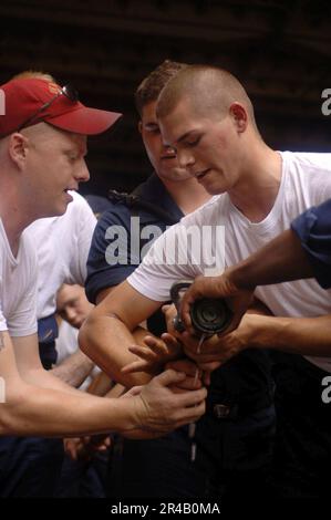 US Navy Schadenskontrolle 1. Klasse zeigt Hull Technician Fireman die richtige Technik zum Lösen der Düsen Stockfoto