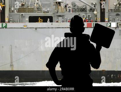 DER MATE Seaman der US Navy Boatswain fungiert als Linienführer bei einer laufenden Auffüllung. Stockfoto