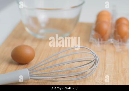 Frische Bio-Eier mit Küchenutensilien auf Holzhintergrund. Koch in der Küche. Ich bereite das Frühstück aus Bauernprodukten und natürlichen Eiern zu. Stockfoto