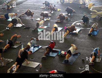 Mitglieder der US Navy des an Bord befindlichen Teams für die Entsorgung von Sprengstoffen führen Matrosen und Marines während eines von Kommandos gesponserten Fitnesstrainings durch verschiedene Übungen. Stockfoto