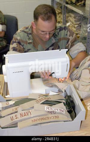 US Navy Storekeeper 3. Class näht Namensschilder auf Desert Utility Uniformen für Navy Reservisten, die vor kurzem mobilisiert wurden. Stockfoto