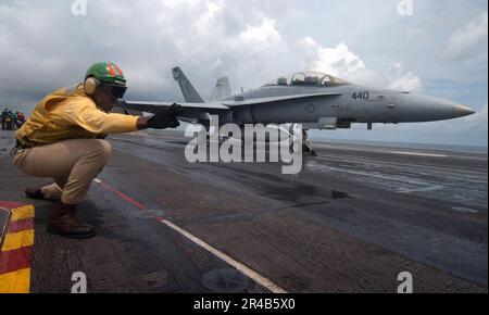 US Navy LT. Ein Schütze, der dem Air Department zugeteilt ist, gibt das Signal, eine F-A-18D Hornet zu starten. Stockfoto