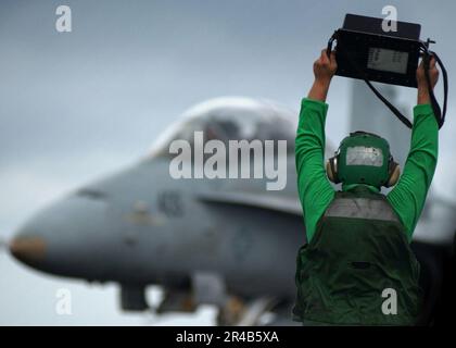 US Navy Airman, dem Air Department zugeteilt, hält ein Gewichtstafel hoch, das die Piloten sehen können, während sie ihre F-A-18D Hornet Rollen. Stockfoto