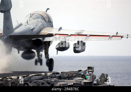 US Navy Airman, der Catapult One Bow Sicherheitsbeobachter, duckt sich, während ein EA-6B Prowler vom Flugdeck startet. Stockfoto