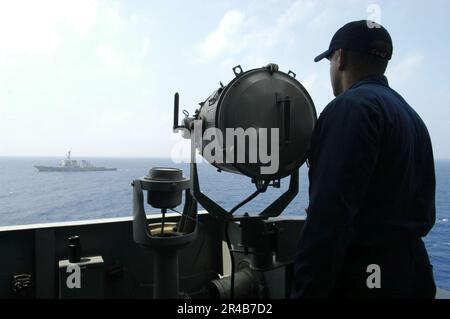 US Navy Quartermaster 2. Class verwendet Blitzlicht, um mit dem gesteuerten Raketenzerstörer USS Fitzgerald (DDG 62) zu kommunizieren. Stockfoto