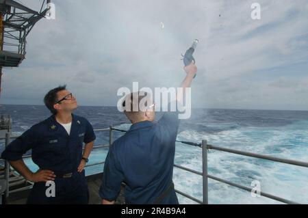 US Navy Gunner's Mate 1. Class beobachtet, wie ein Waffeninstitut Sailor eine Leuchtpistole vom Fantail abfeuert Stockfoto