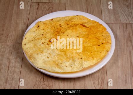 Gebratener Papad in weißer Platte auf Holzhintergrund. Stockfoto