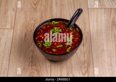 Vegetarische Manchow-Suppe in schwarzer Schüssel auf Holzhintergrund Stockfoto